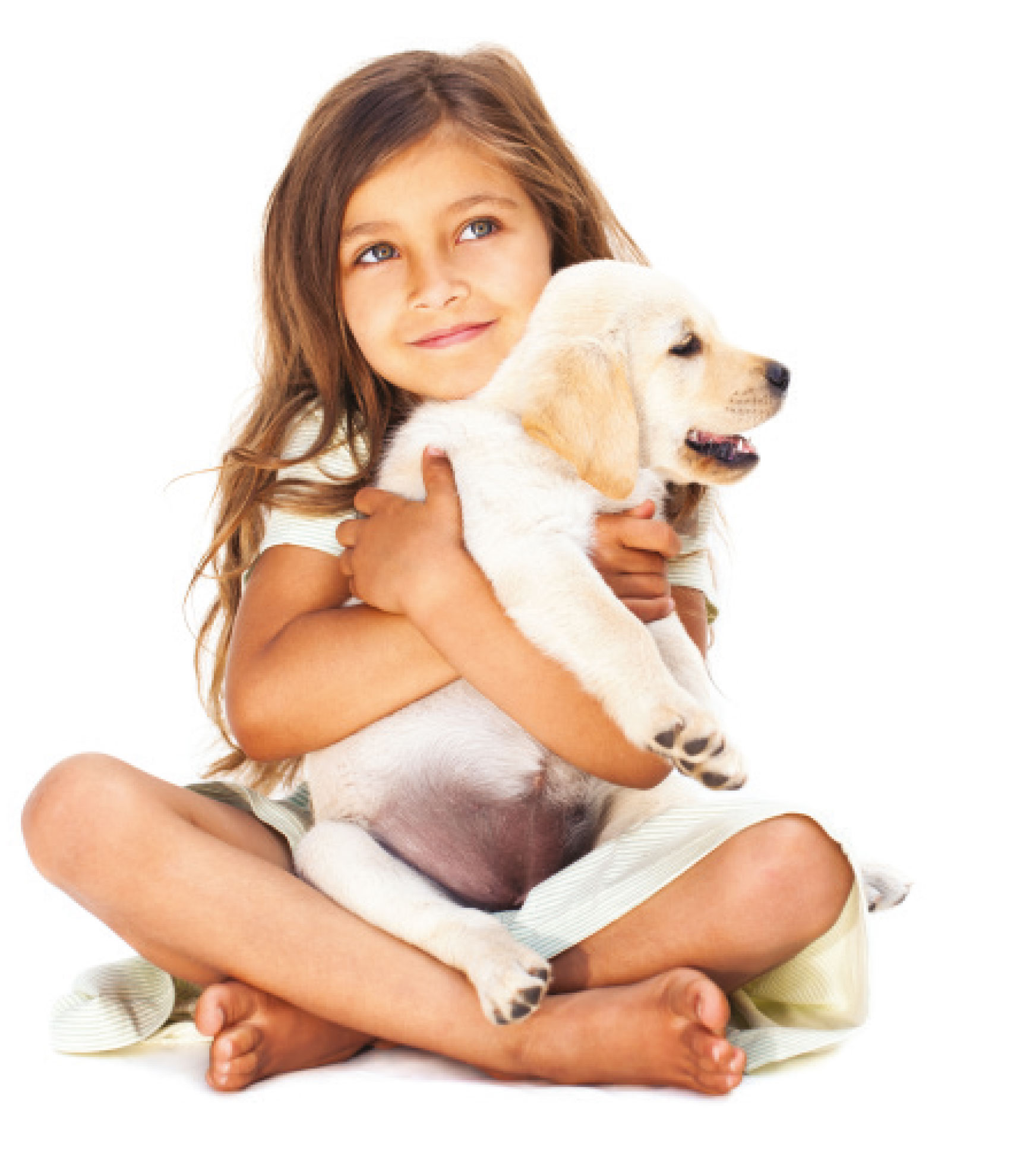 A young girl sitting cross legged on the floor cuddling a labrador puppy